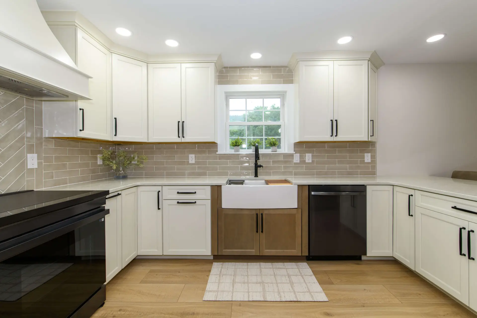 Bright modern kitchen with white cabinets, beige subway tile backsplash, and a double-wall sink under a window center stage.
