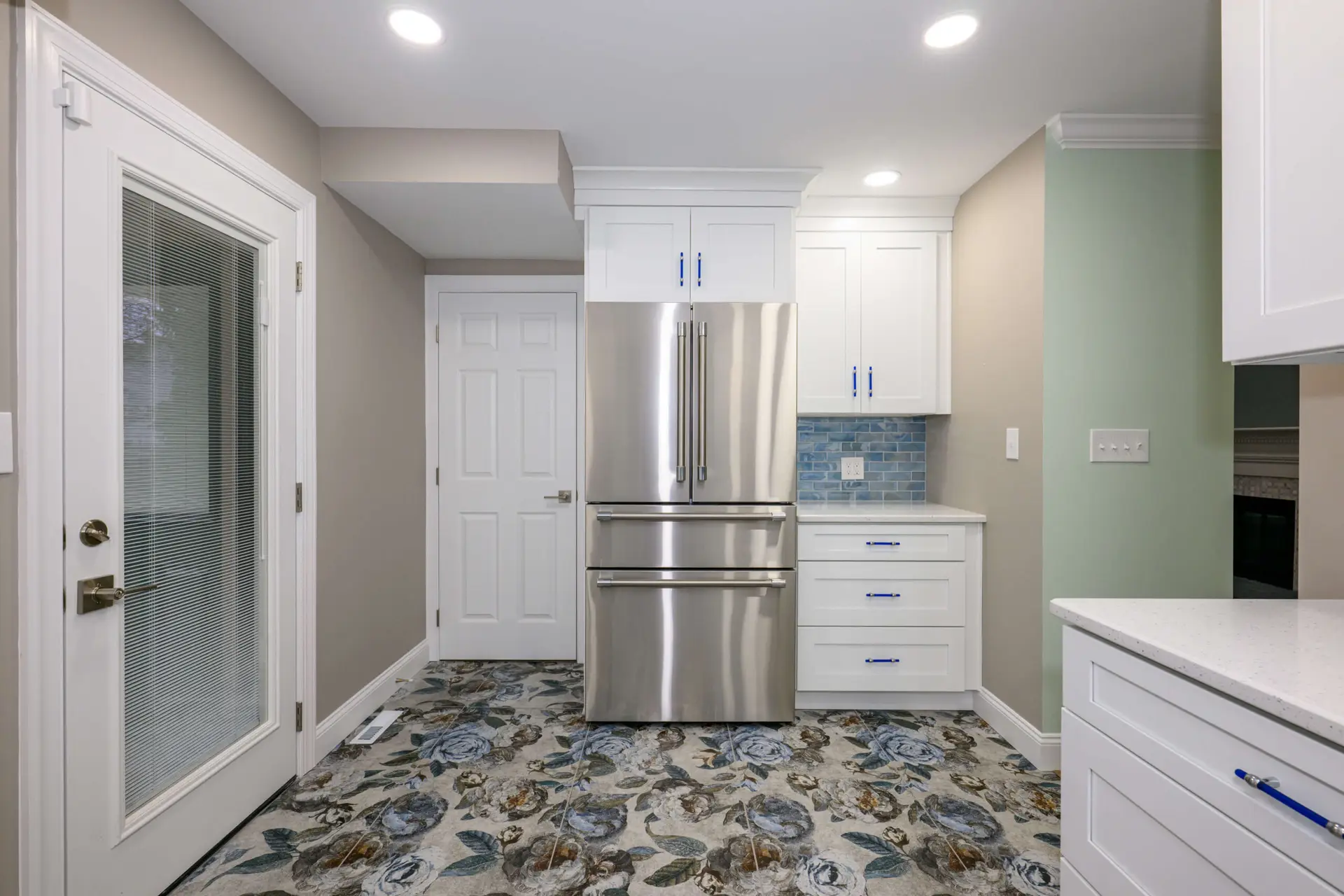 Modern kitchen with white cabinets, stainless steel French-door fridge, and a floral-patterned tile floor.