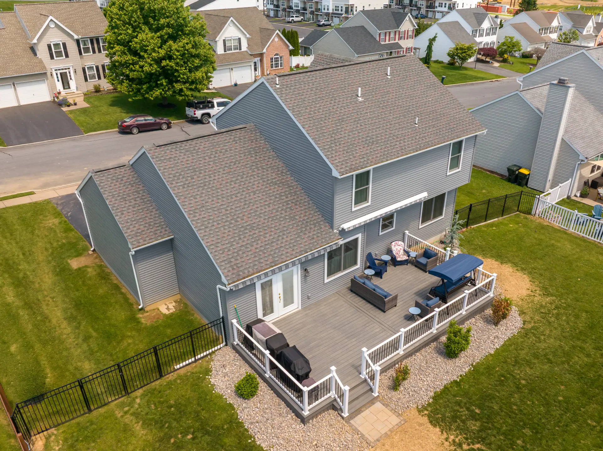 Aerial view of a suburban cul-de-sac with gray two‑story houses, backyards, and decks.