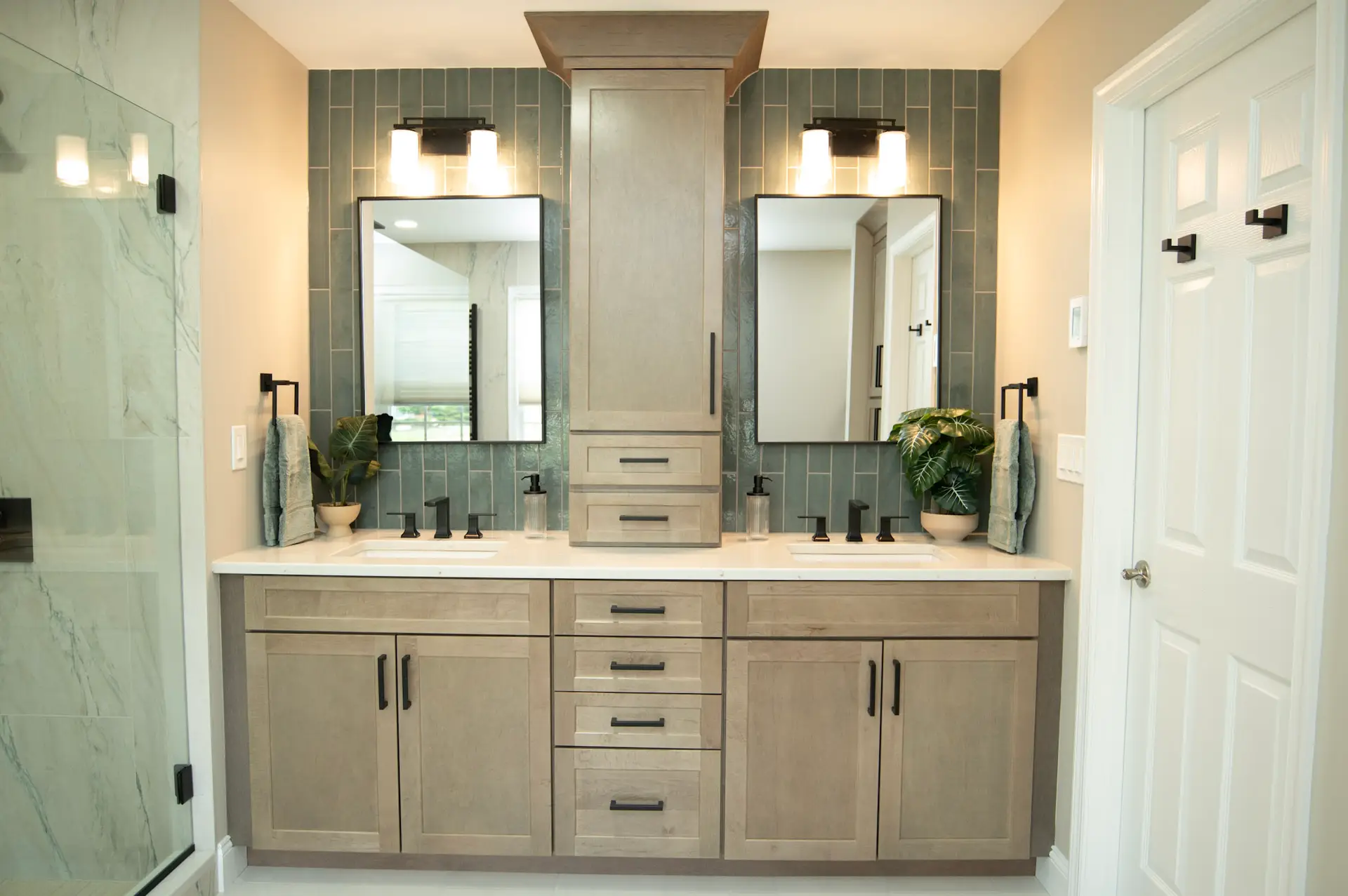 Double-sink bathroom vanity with gray wood cabinets, two mirrors, and black fixtures against a blue tile backsplash.